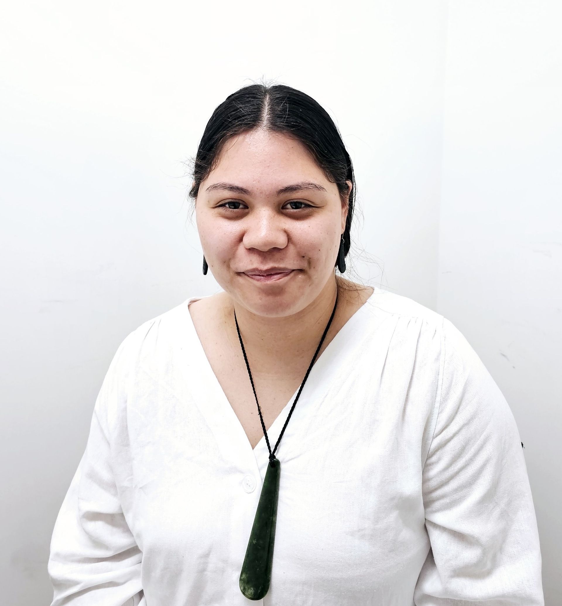 A woman wearing a white shirt and a green necklace