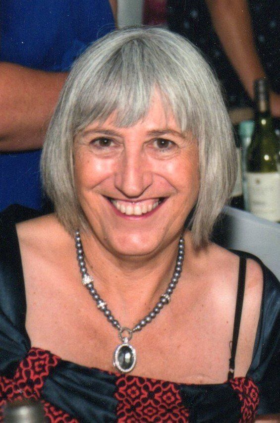 A woman wearing a necklace is smiling for the camera