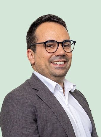 A man wearing glasses and a suit is smiling for the camera.