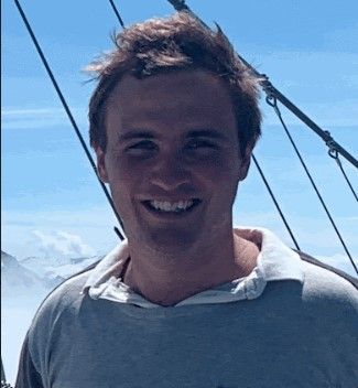A man is smiling for the camera while standing on a boat.
