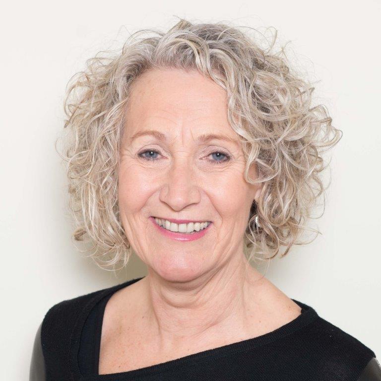 A woman with curly hair is smiling and wearing a black shirt