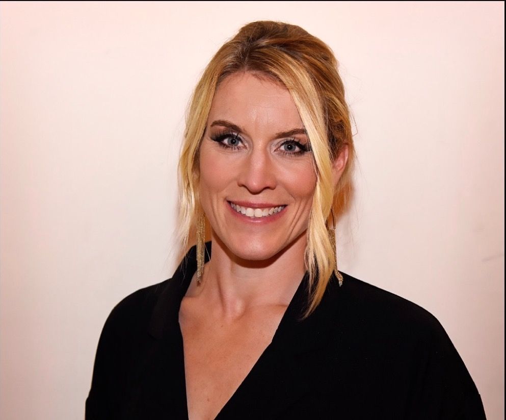 A woman in a black shirt is smiling for the camera.