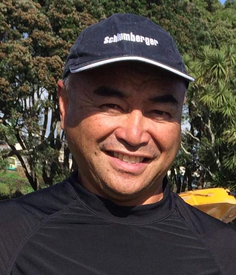 A man wearing a black shirt and a blue hat is smiling.