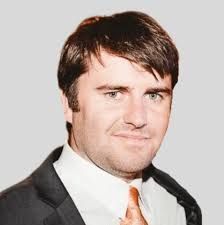 A man in a suit and tie is smiling for the camera.