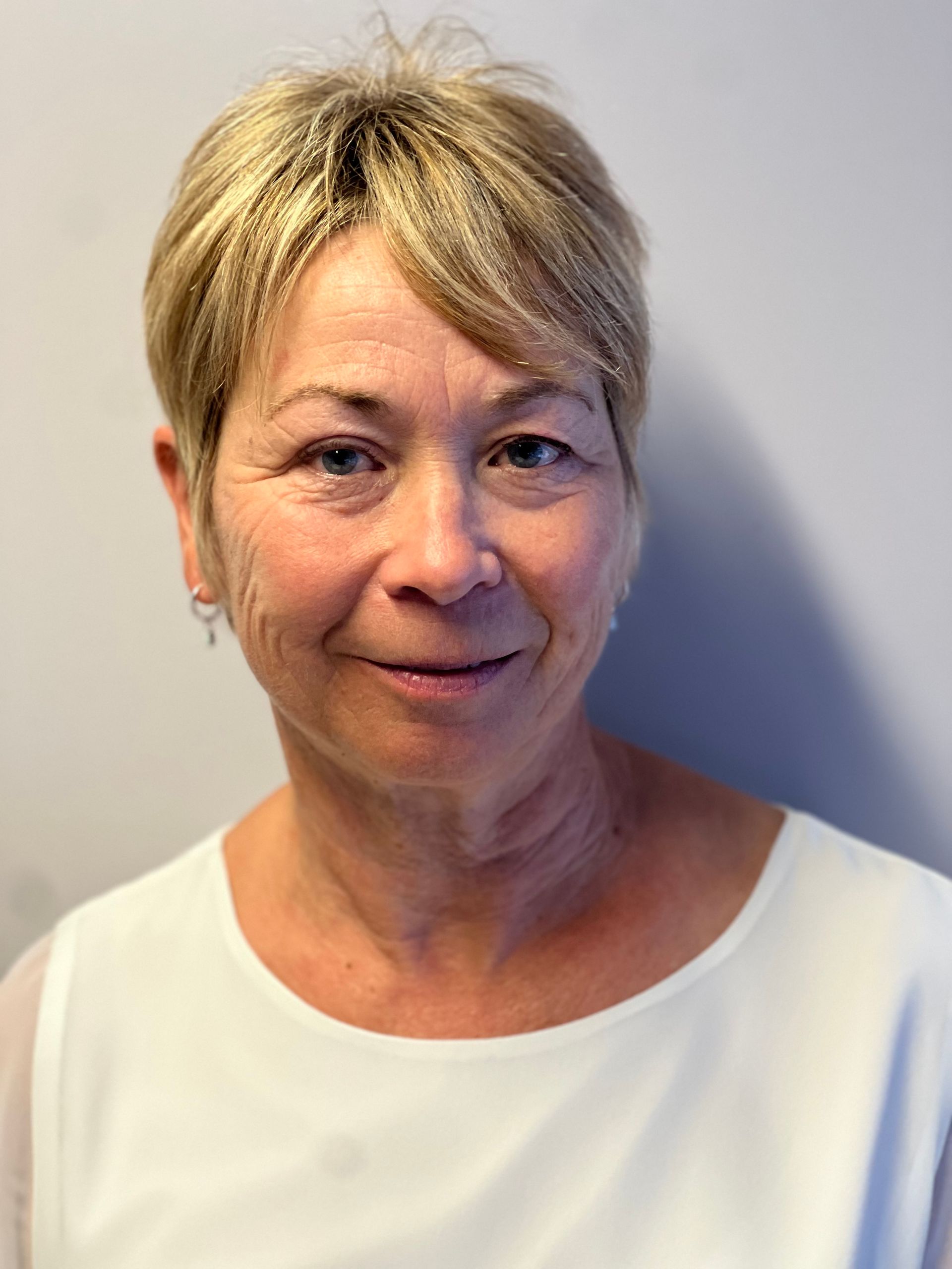 A woman in a white shirt is smiling for the camera.