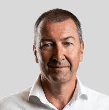 A man in a white shirt is smiling for the camera.