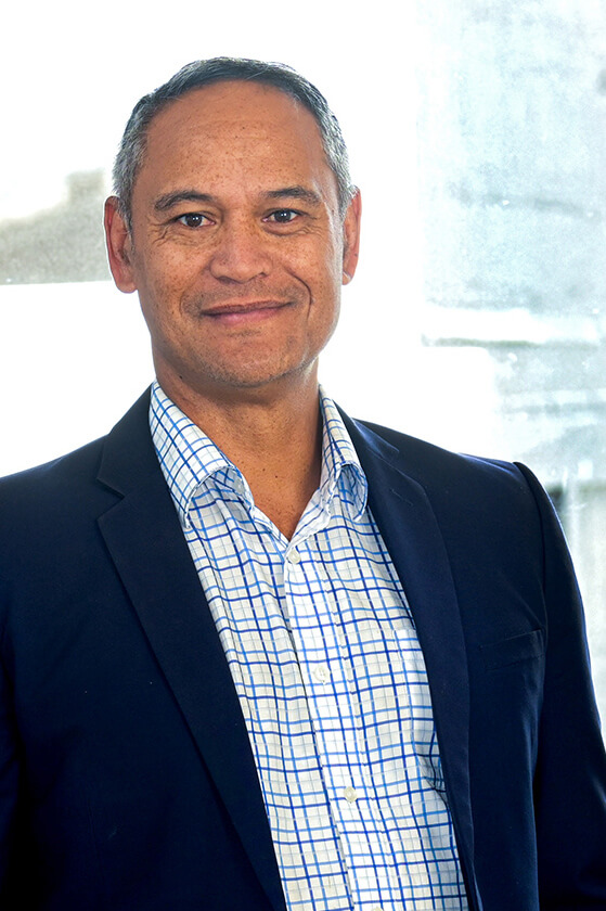 A man in a suit and plaid shirt is smiling for the camera.