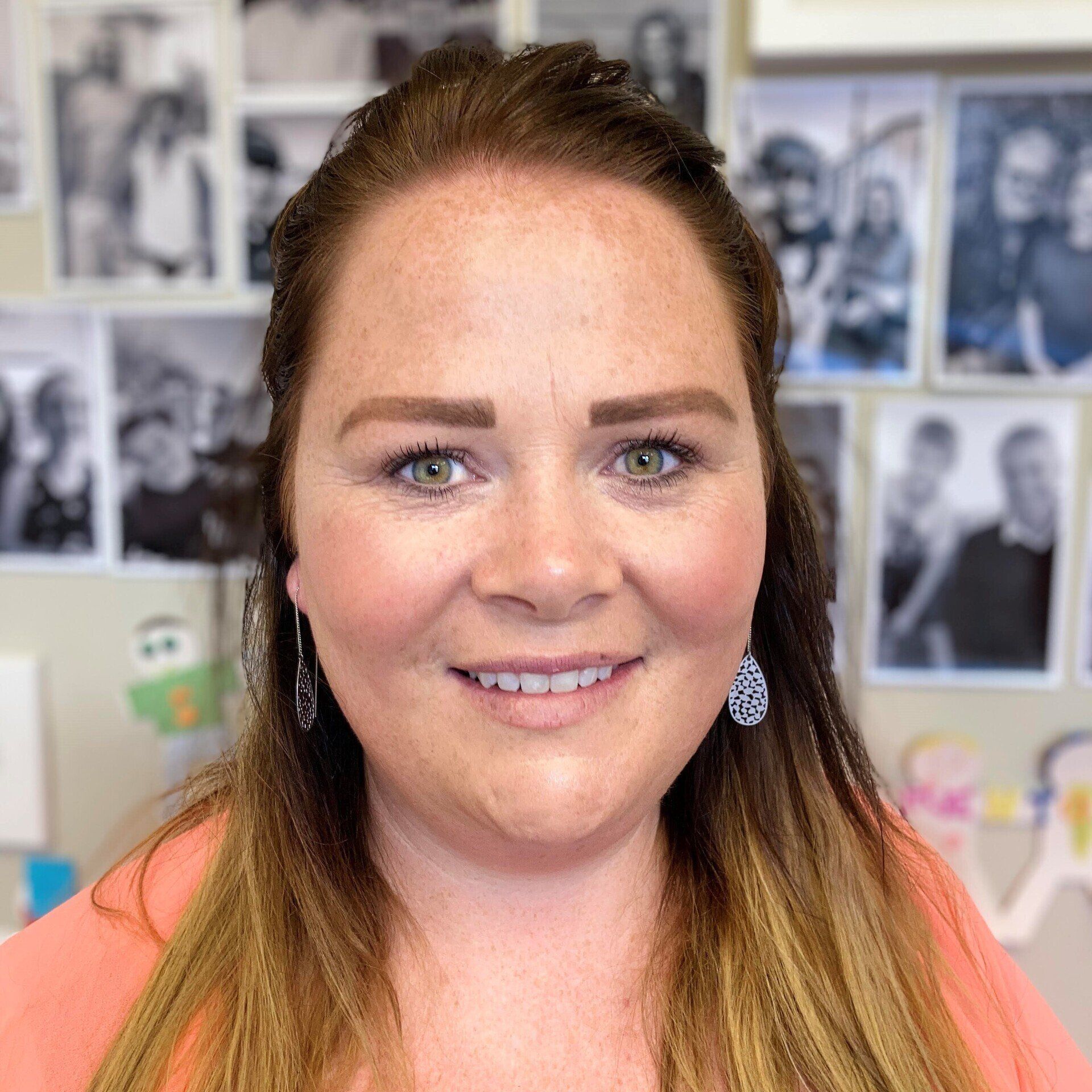 A woman is smiling for the camera in front of a wall of pictures.
