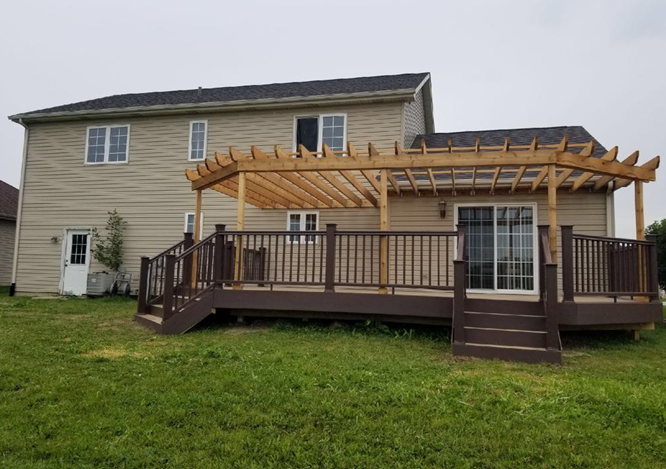 Man kneels, hammering a door frame outside a structure with an open door; tools and forest visible.
