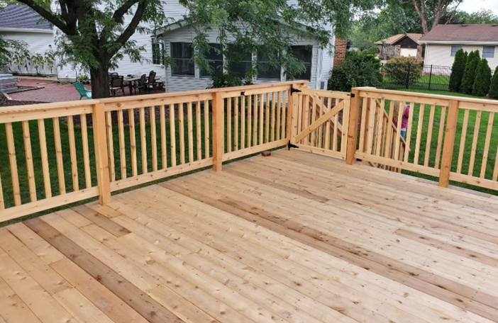 A weathered wooden deck attached to a light blue house. Red railing, sliding door, and window visible.