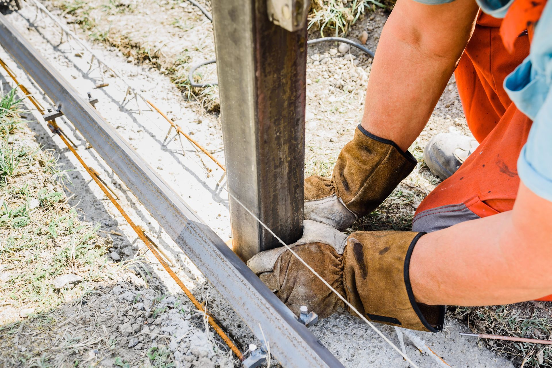 Person wearing gloves working on metal construction outdoors.