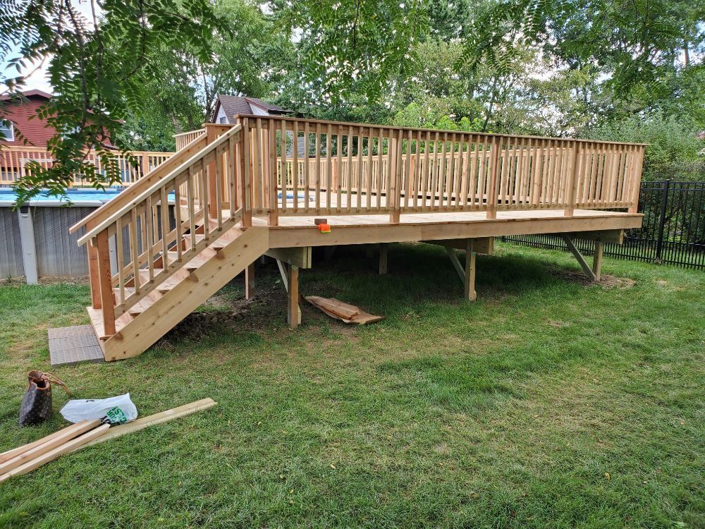 Wooden deck with stairs and railing in a grassy backyard.