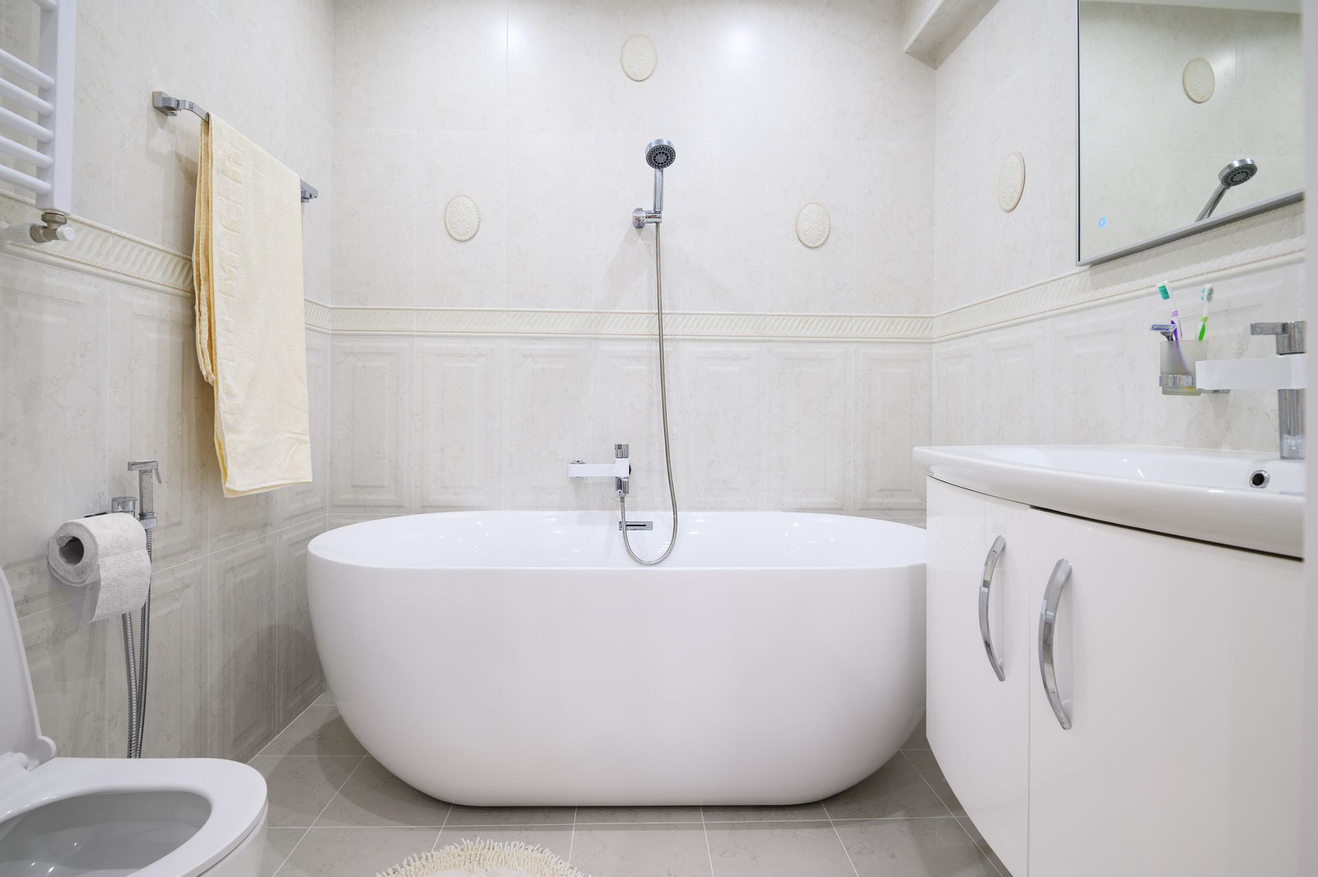 Modern white bathroom with a bathtub, toilet, sink, and towel rack.