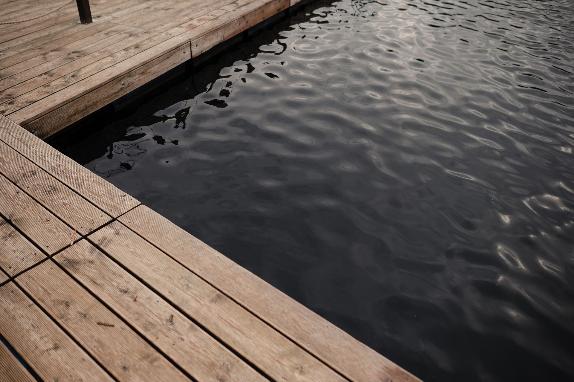 Wooden dock edge bordering dark, rippled water.