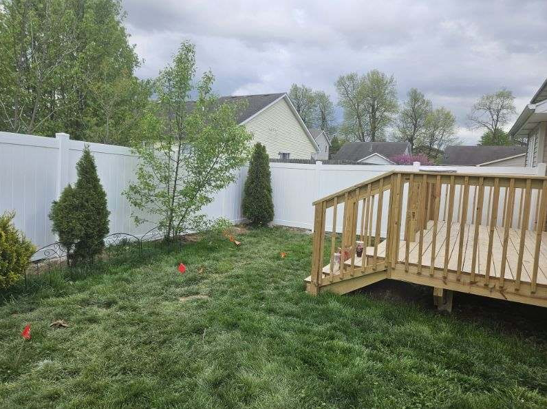 A person in red gloves painting a white picket fence with a paintbrush outdoors.