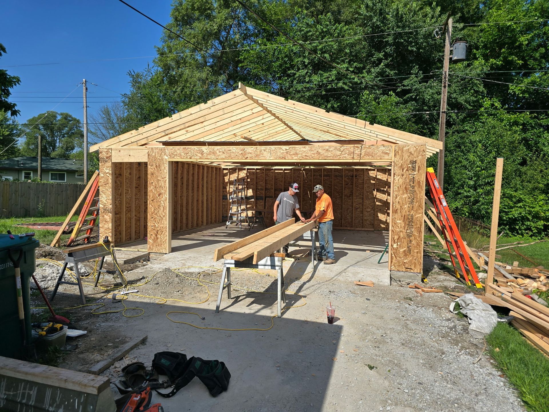 Woodworking workshop with tools, workbenches, wood, and industrial lighting.