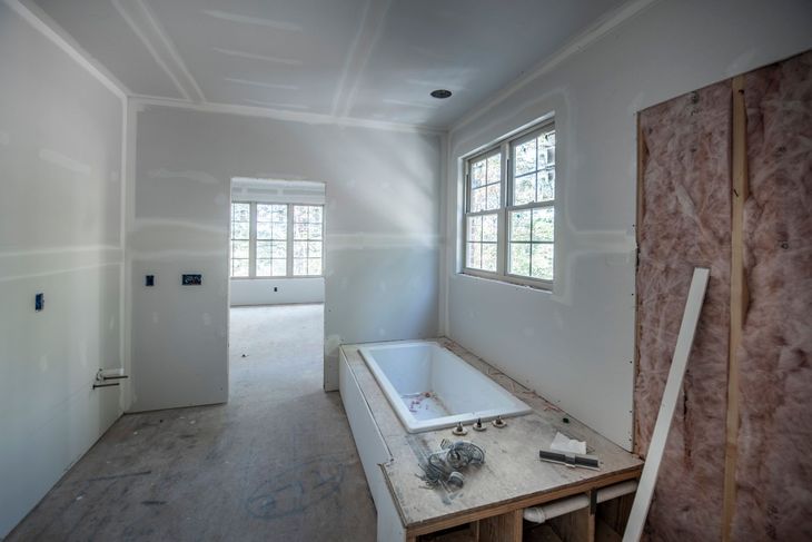 Bathroom under construction with a bathtub, window, doorway, and insulation visible.