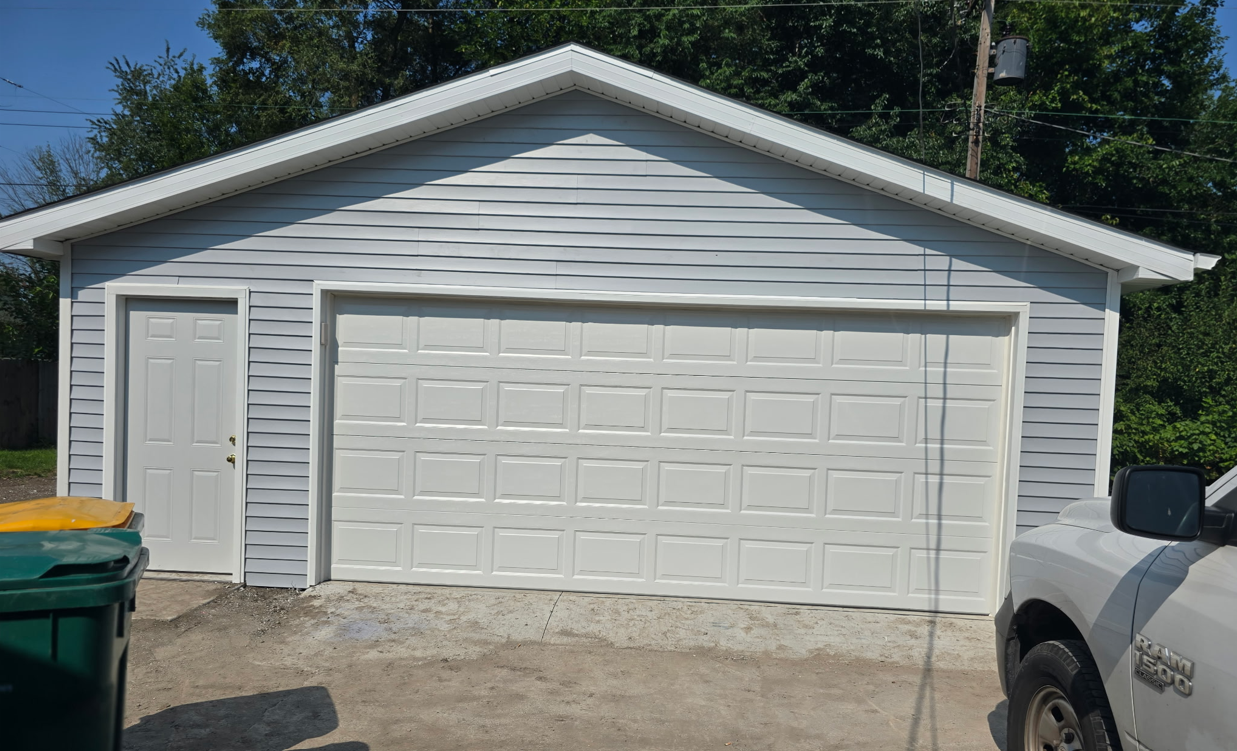 Light blue garage with white trim and a closed garage door and a side door.