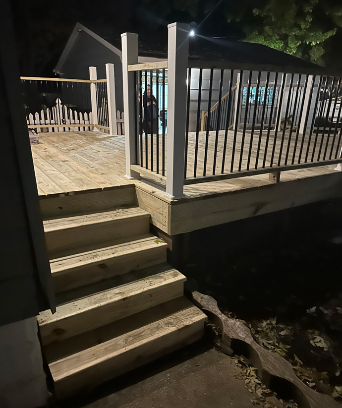 Two people building a wooden deck in a backyard, sunny day.
