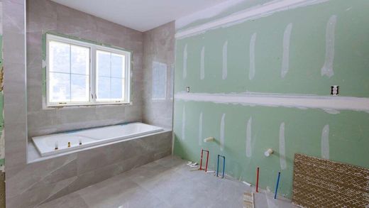 Bathroom renovation in progress: green drywall, tiled tub surround, window, and plumbing fixtures.