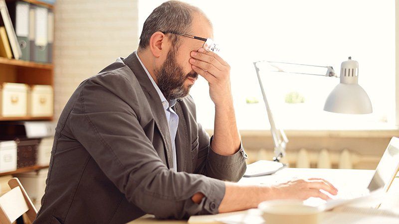 man at desk with hand on face