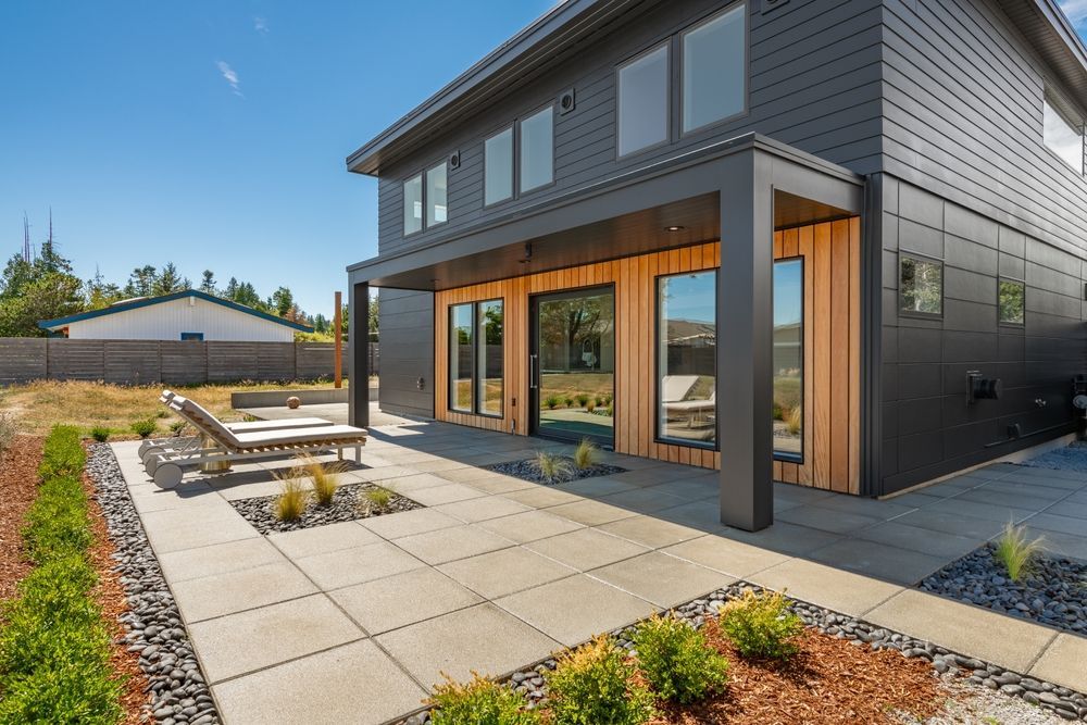 A large black house with a patio and chairs in front of it.