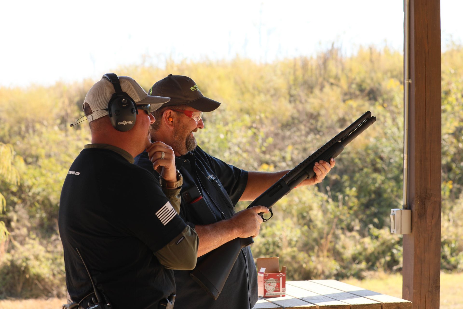 Two men are standing next to each other holding shotguns.