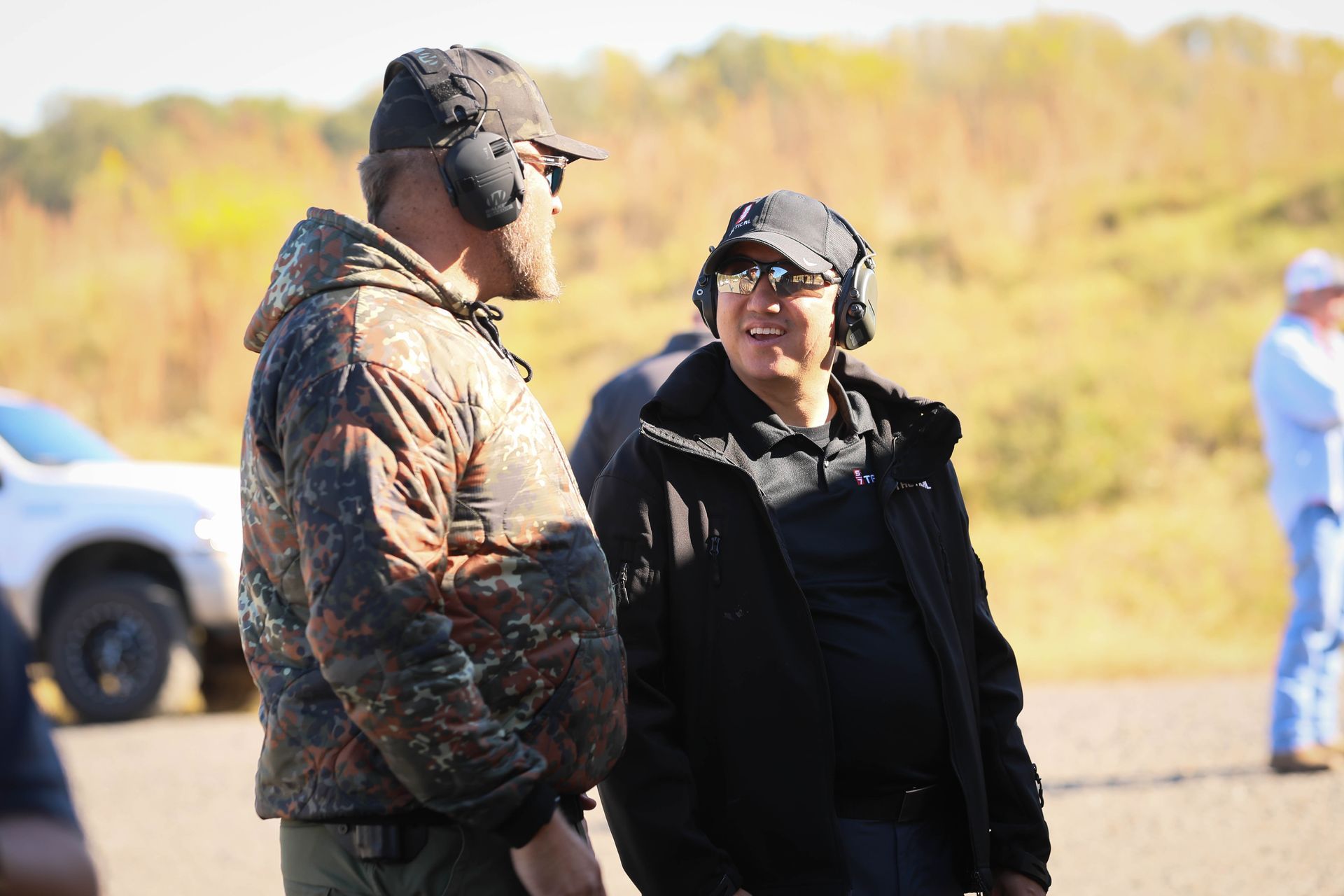 Two men wearing headphones are standing next to each other in a field.