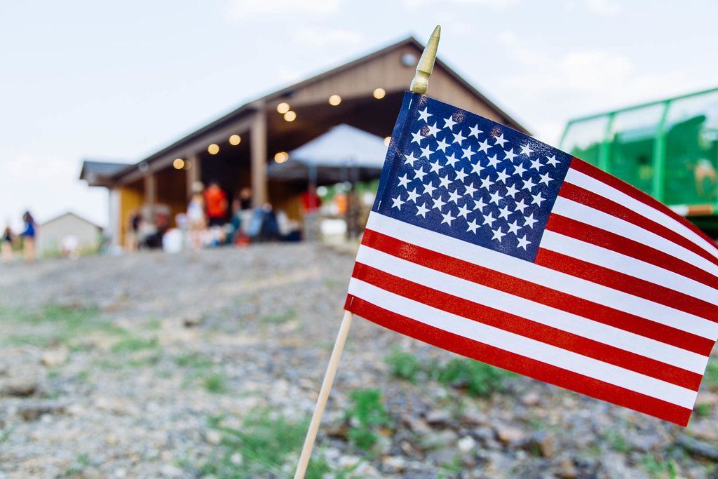 A small american flag is sitting on the ground in front of a building.