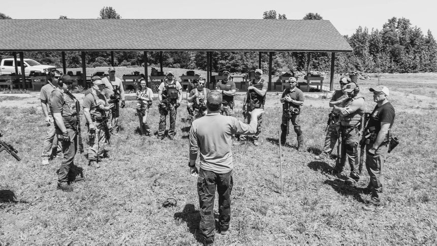 A black and white photo of a group of people standing in a field.