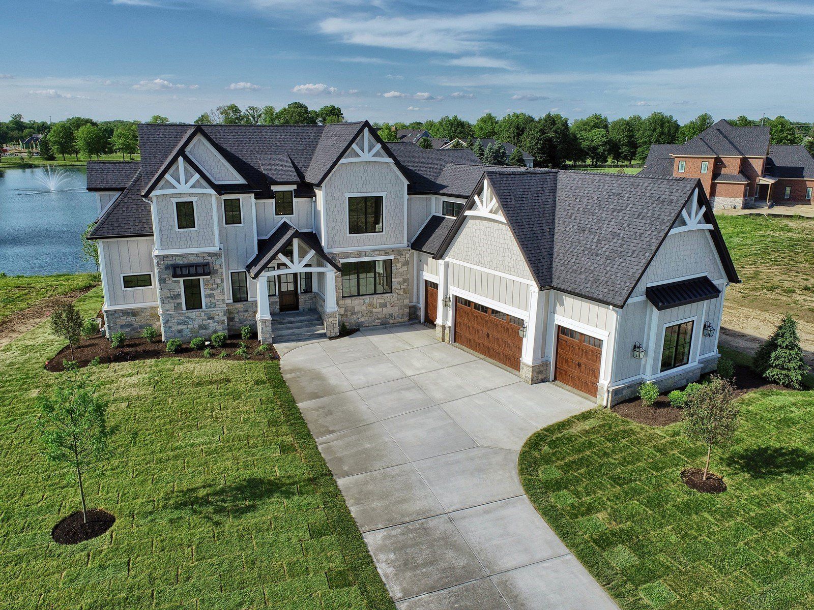 An aerial view of a large white house with a lake in the background.