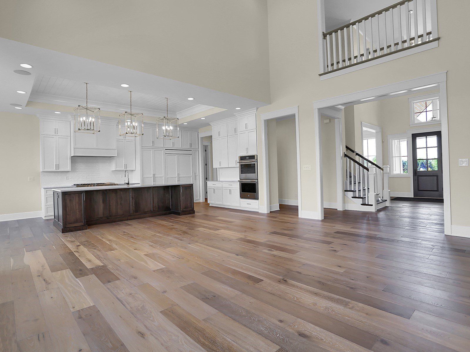 A large empty room with hardwood floors and a kitchen.