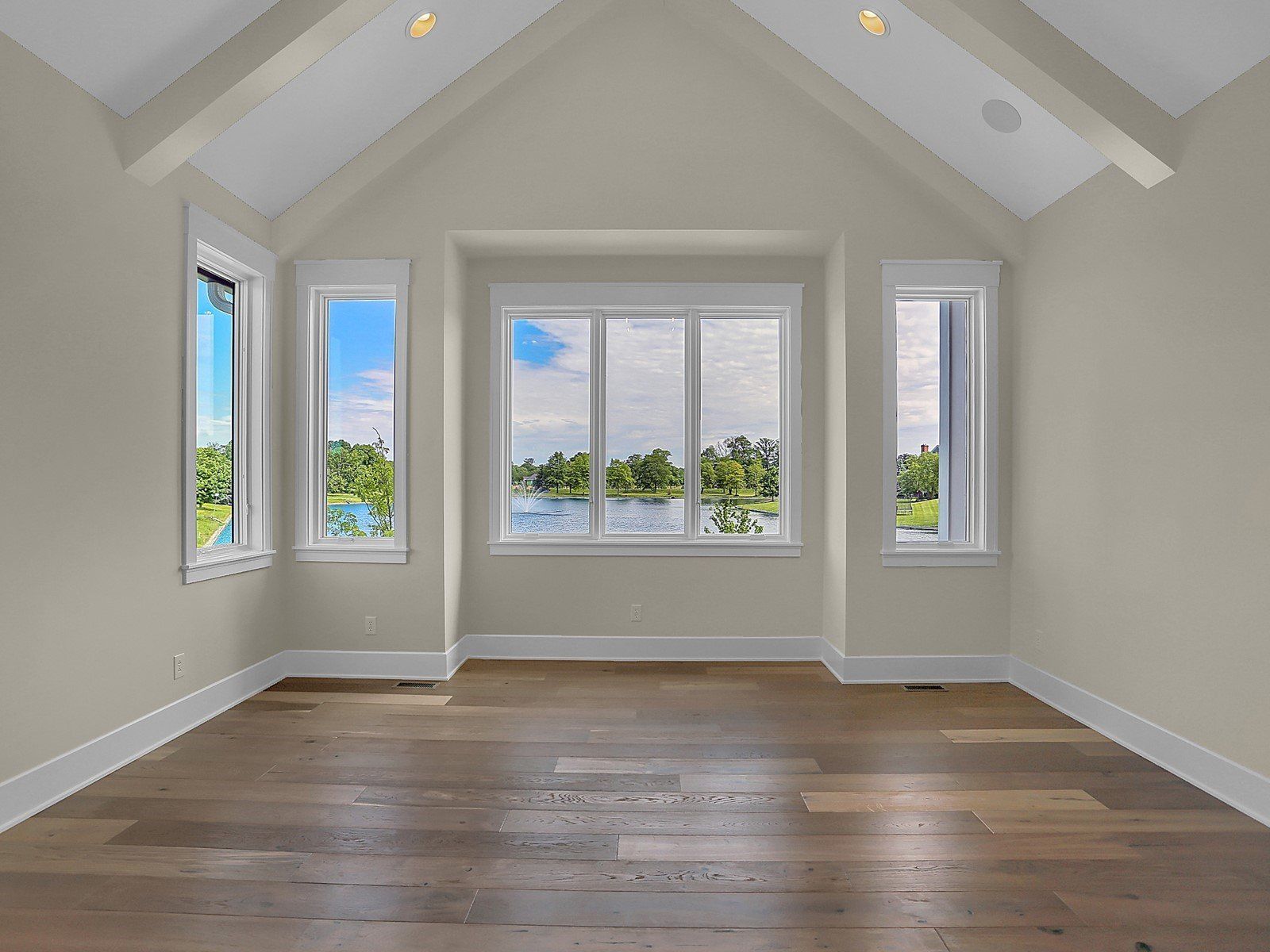 An empty room with a vaulted ceiling and lots of windows.