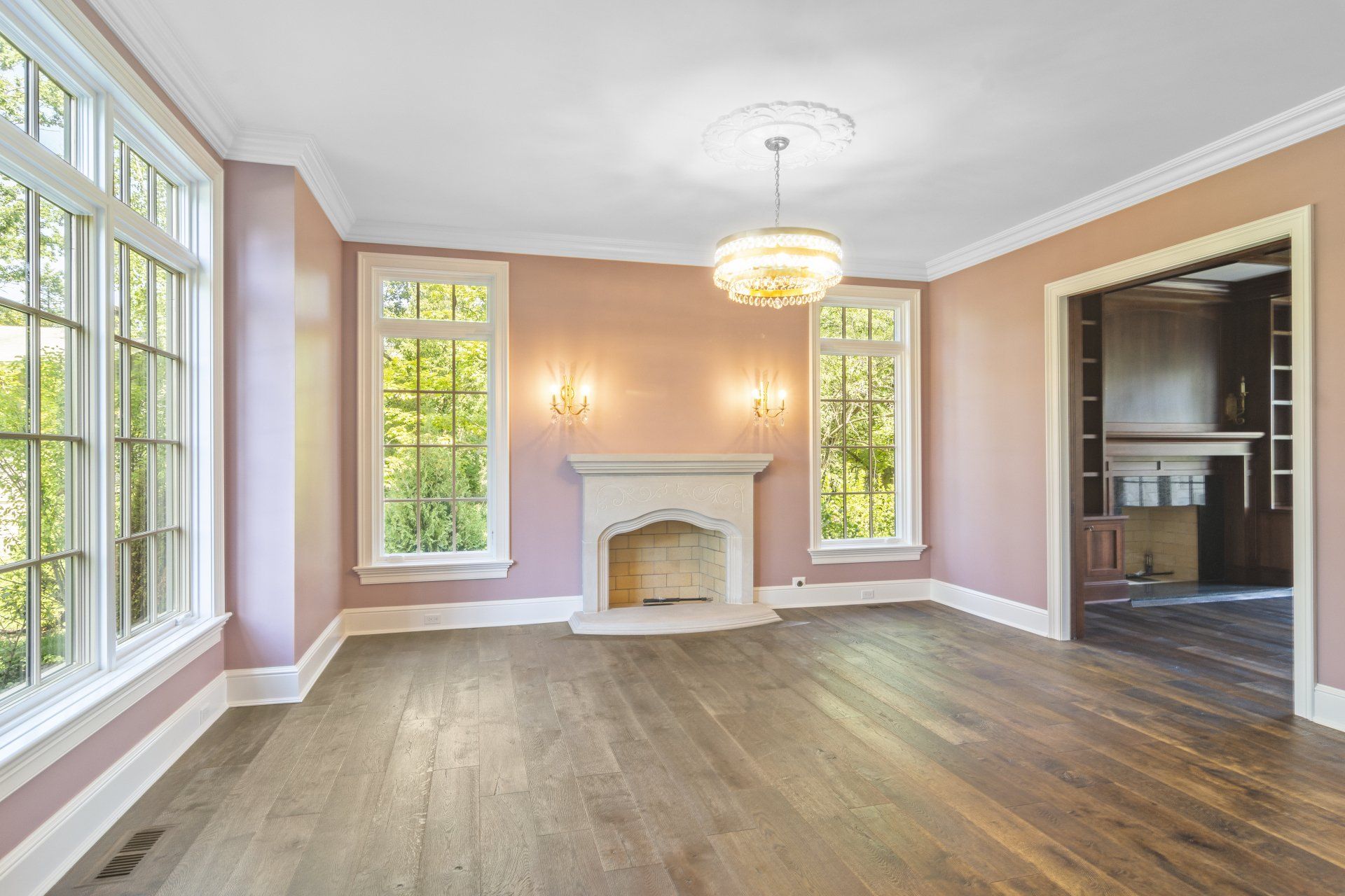 An empty living room with pink walls and a fireplace.