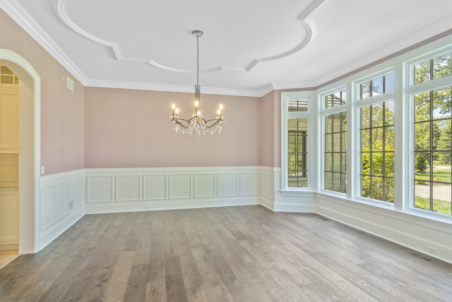 An empty dining room with a chandelier and lots of windows.