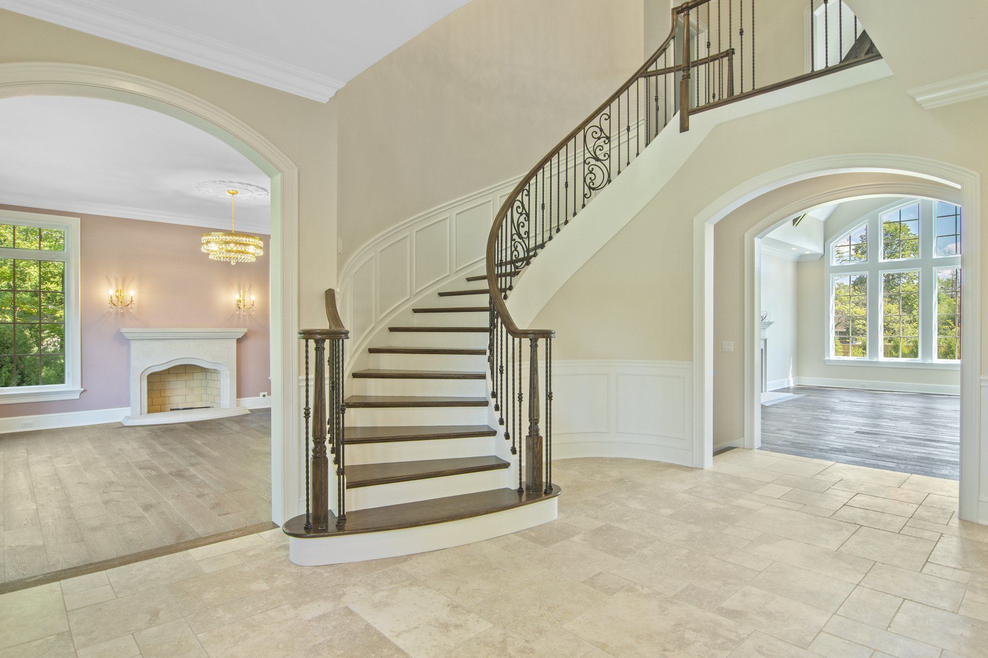 An empty house with a curved staircase and a fireplace.