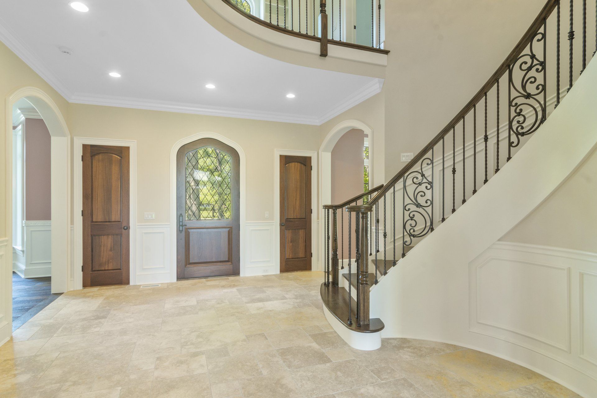 An empty hallway with a curved staircase and a wrought iron railing.
