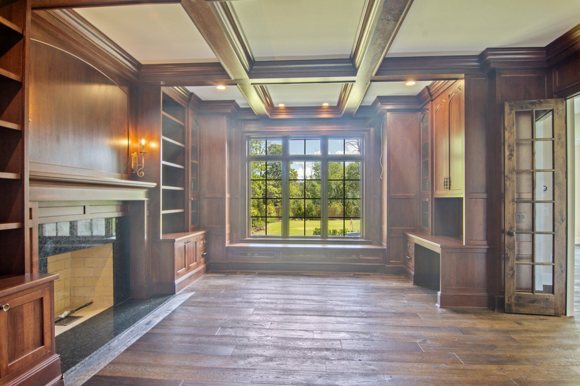 An empty living room with a fireplace and a large window.