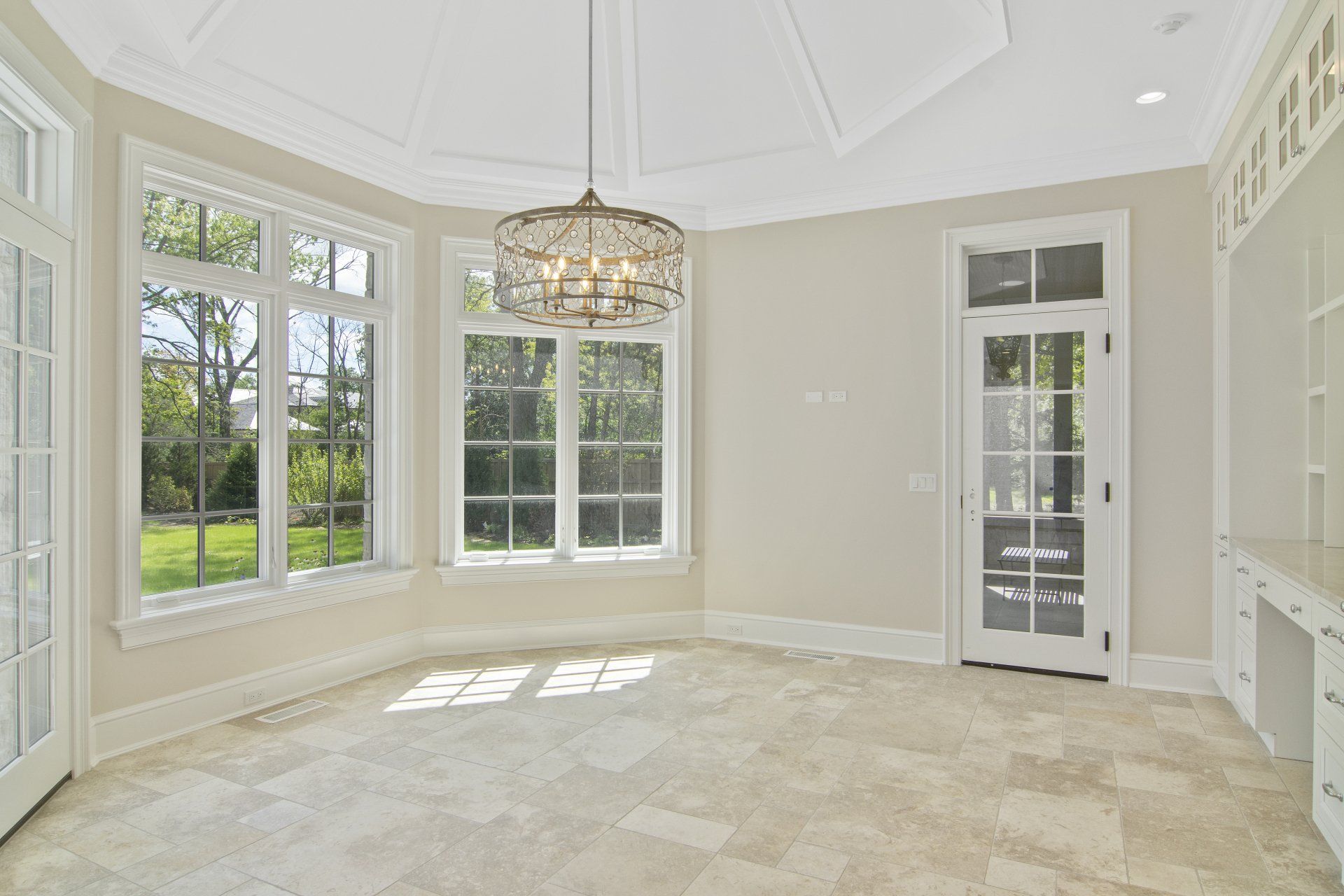 An empty room with a lot of windows and a chandelier.