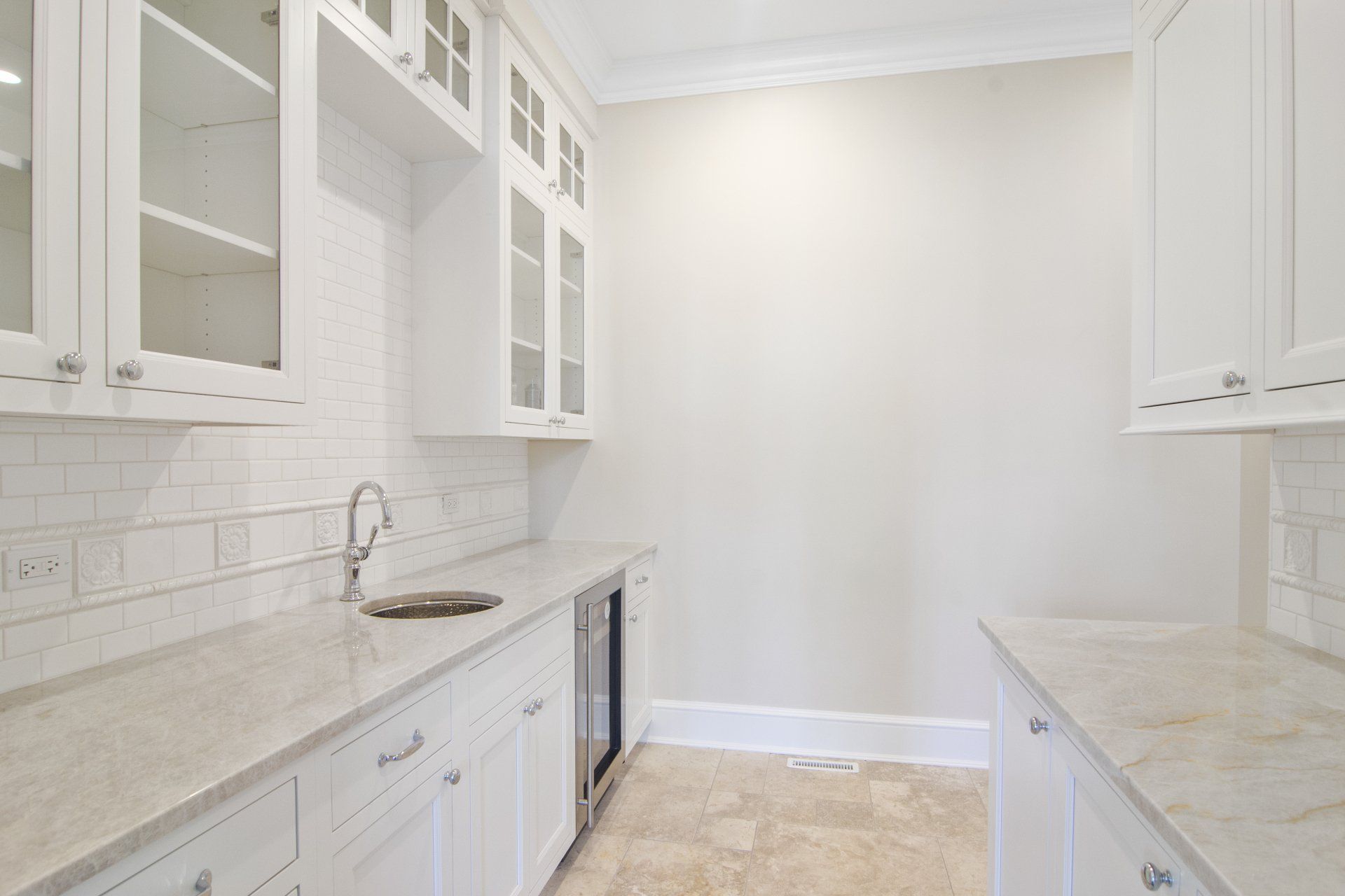 A kitchen with white cabinets , granite counter tops , and a sink.