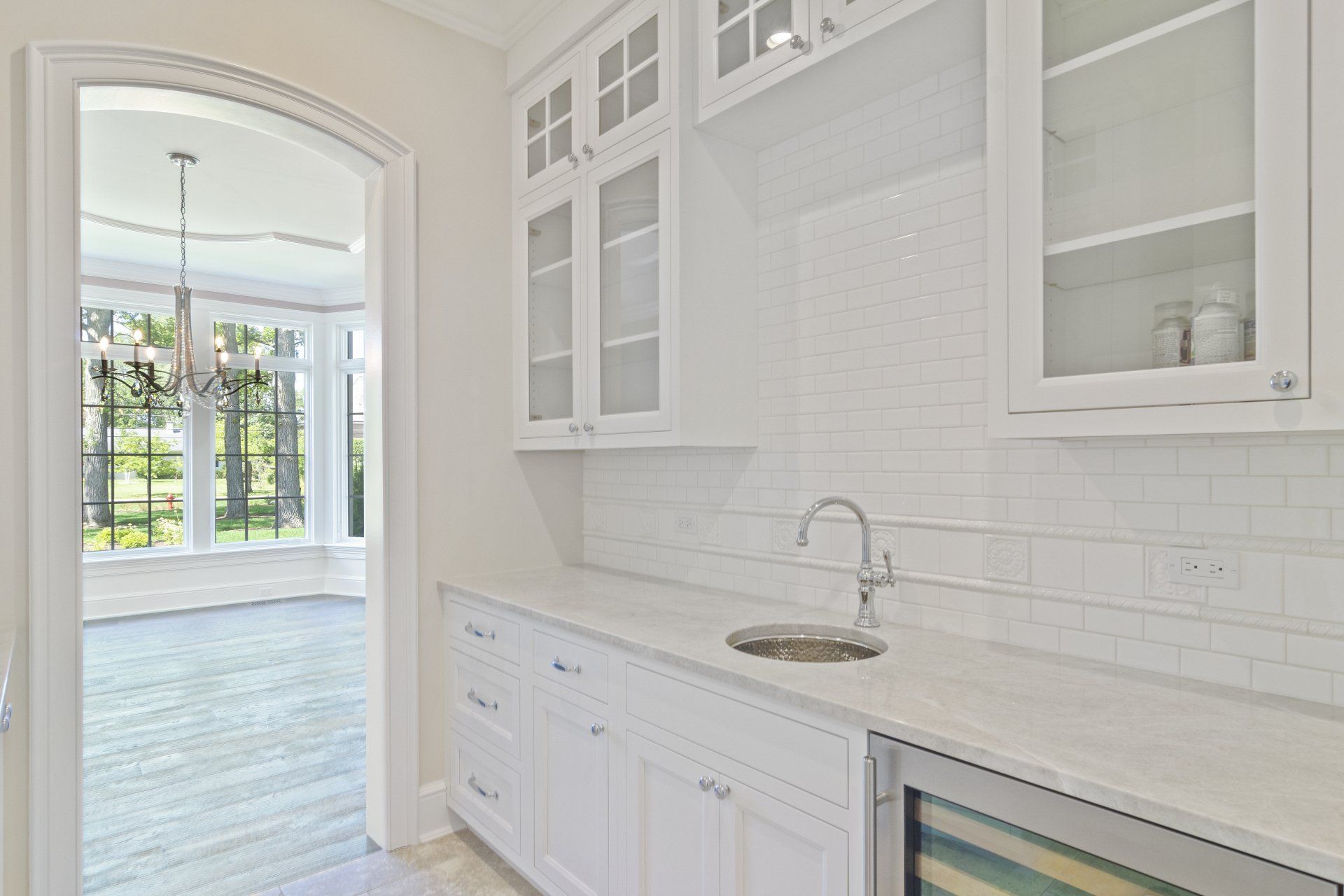 A kitchen with white cabinets , a sink , and a refrigerator.