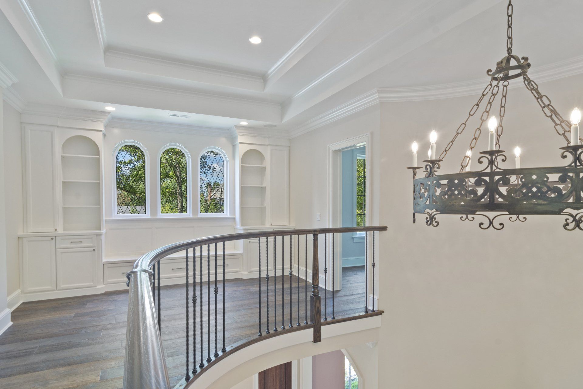 An empty room with a curved railing and a chandelier hanging from the ceiling.