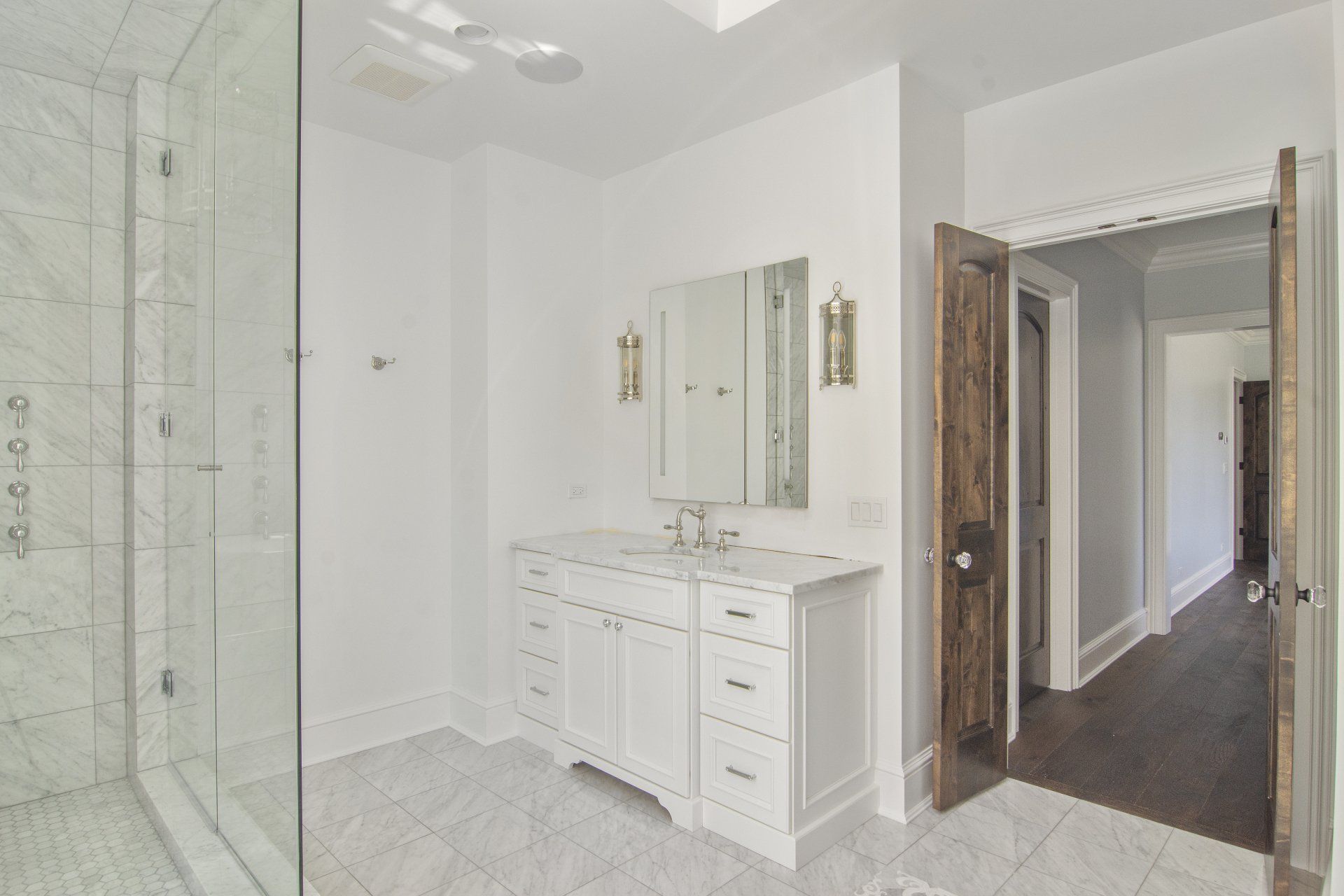 A bathroom with a walk in shower , sink and mirror.