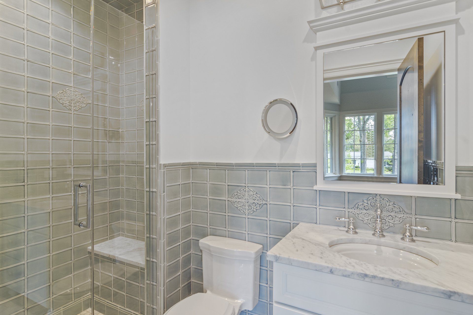 A bathroom with a toilet , sink , mirror and walk in shower.