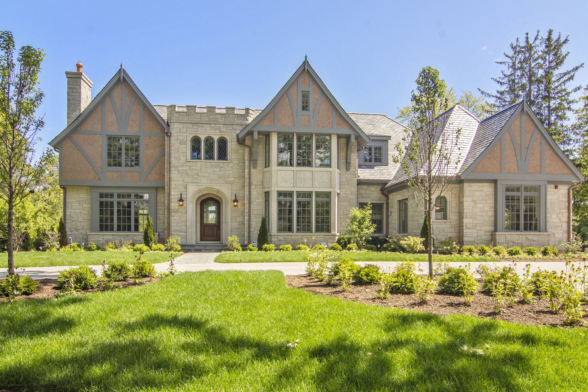 A large house with a lot of windows is sitting on top of a lush green lawn.
