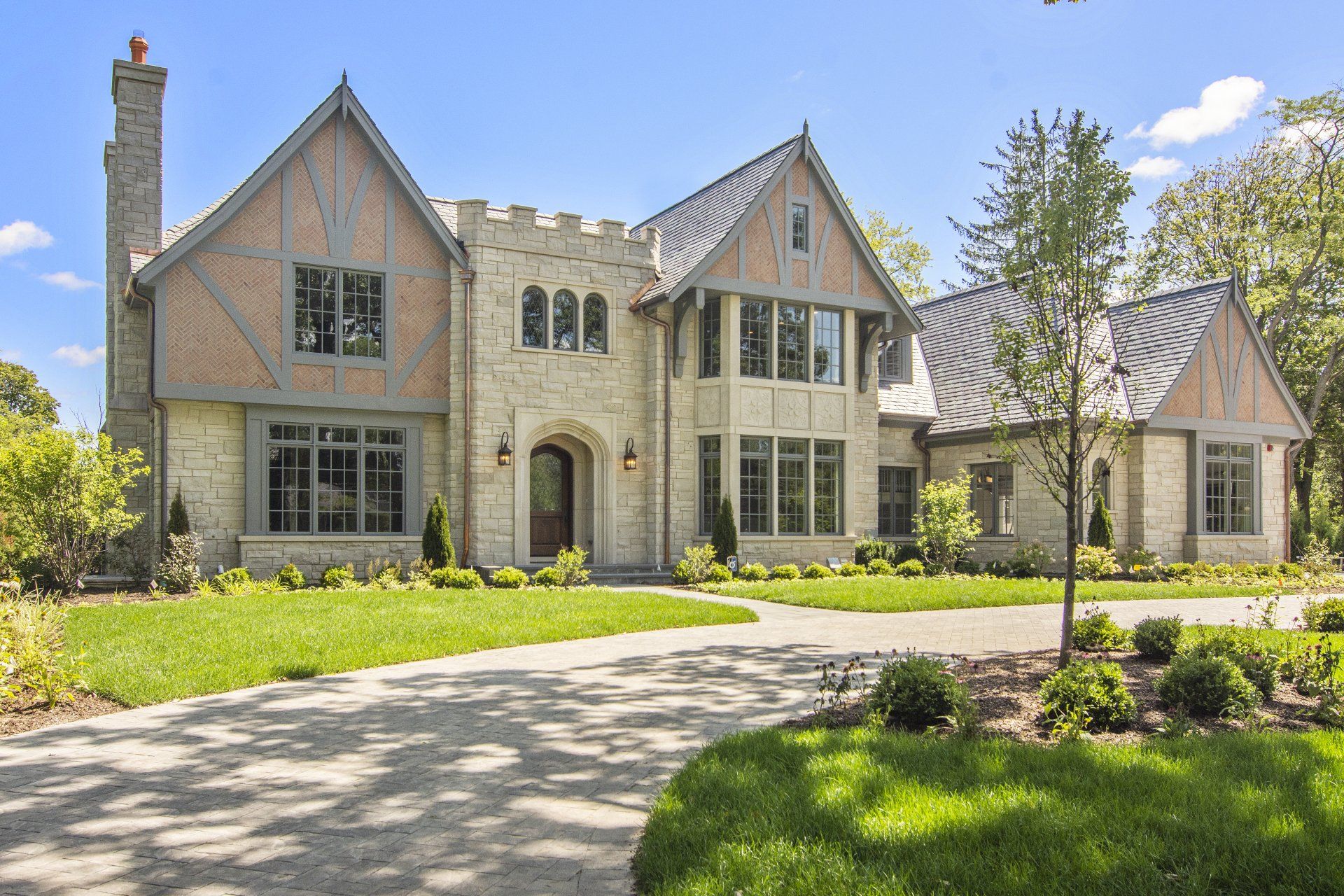 A large house with a lot of windows is sitting on top of a lush green lawn.