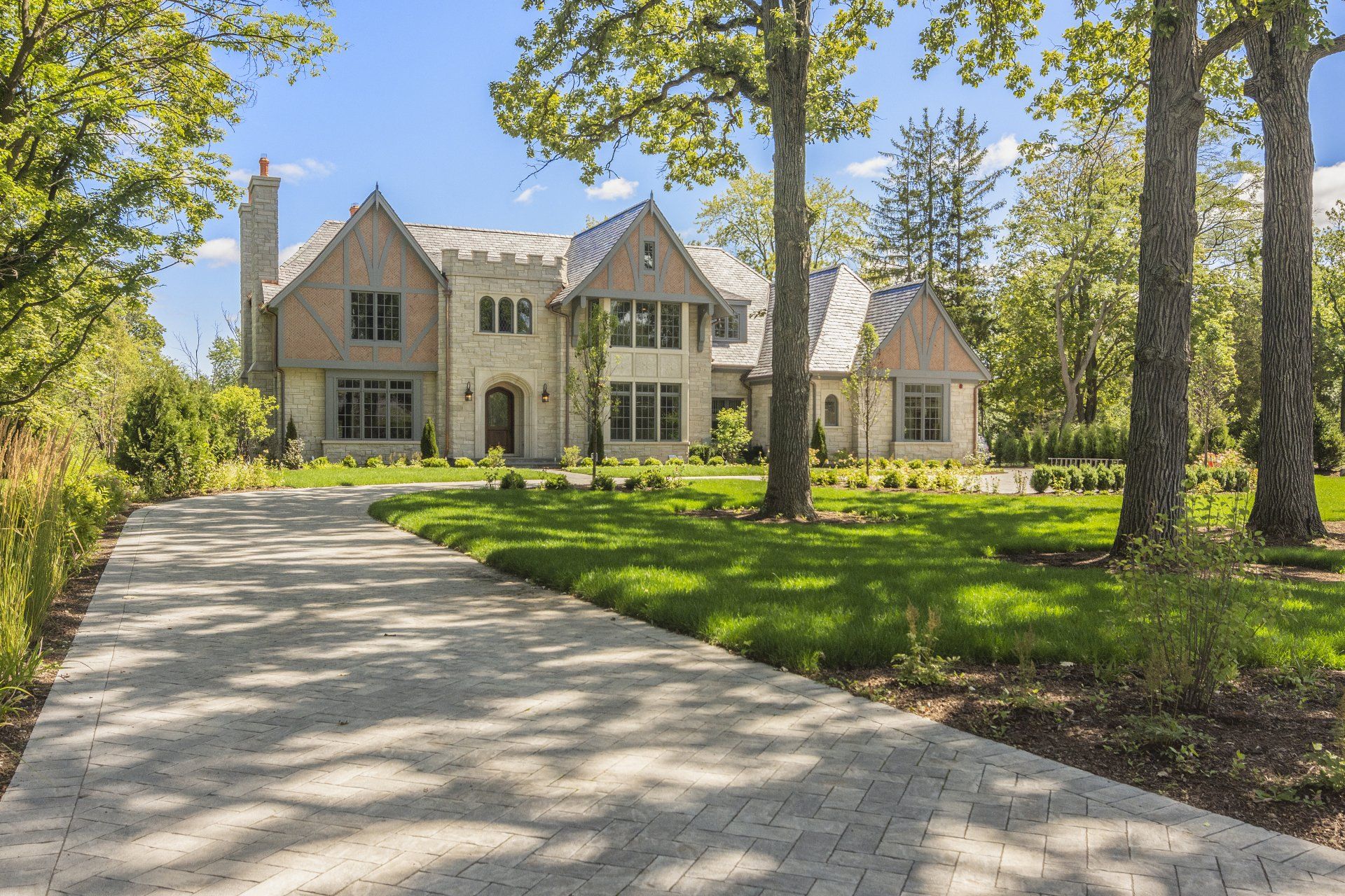 A large house with a driveway leading to it is surrounded by trees.