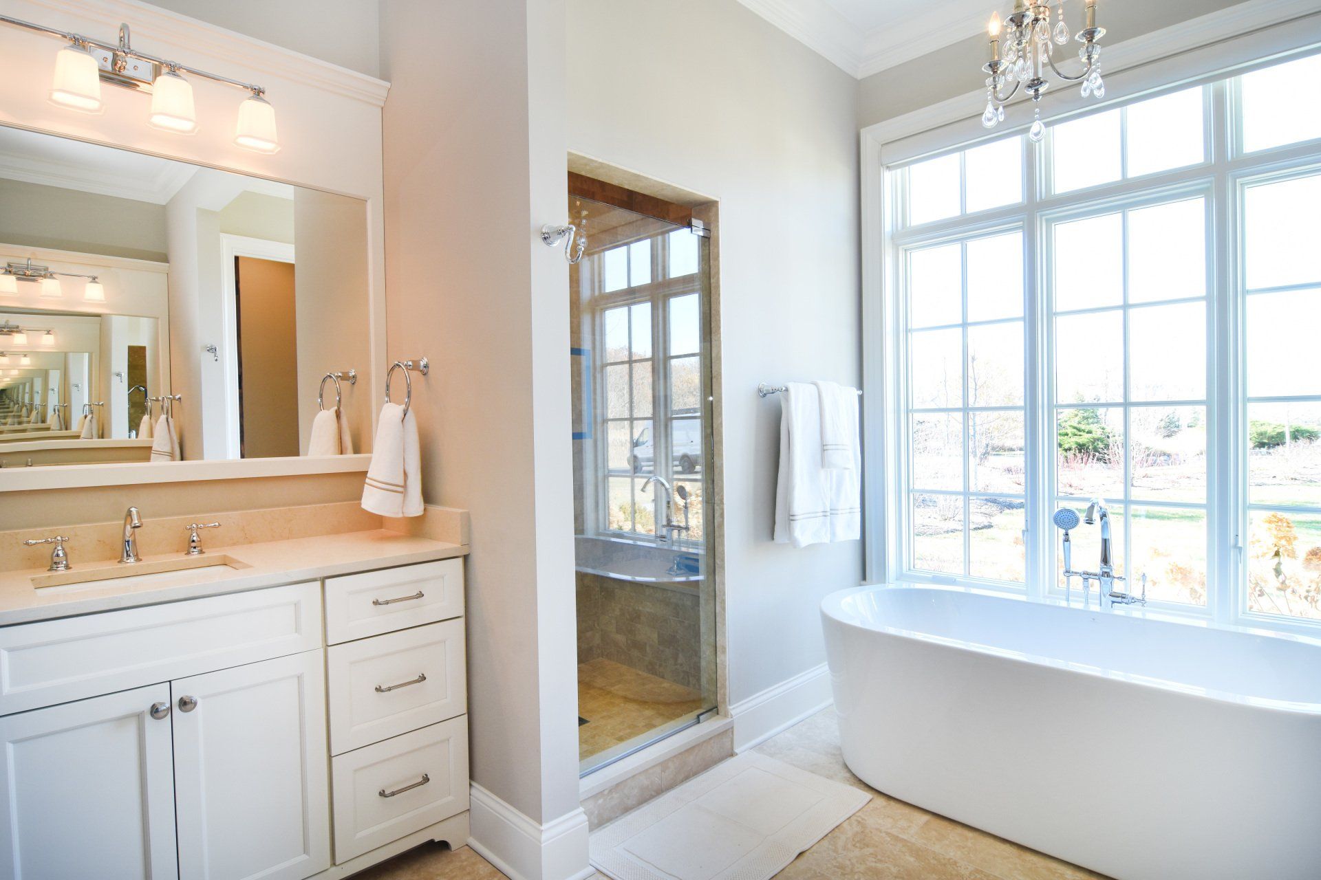A bathroom with two sinks , a tub , a shower and a large window.