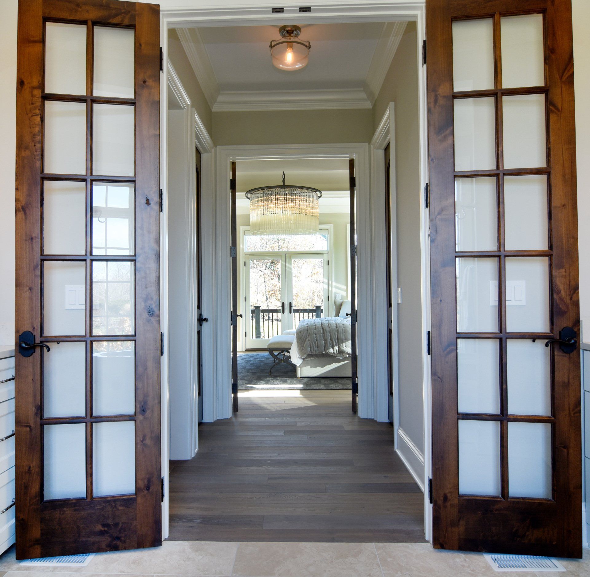 A hallway with french doors leading to a bedroom