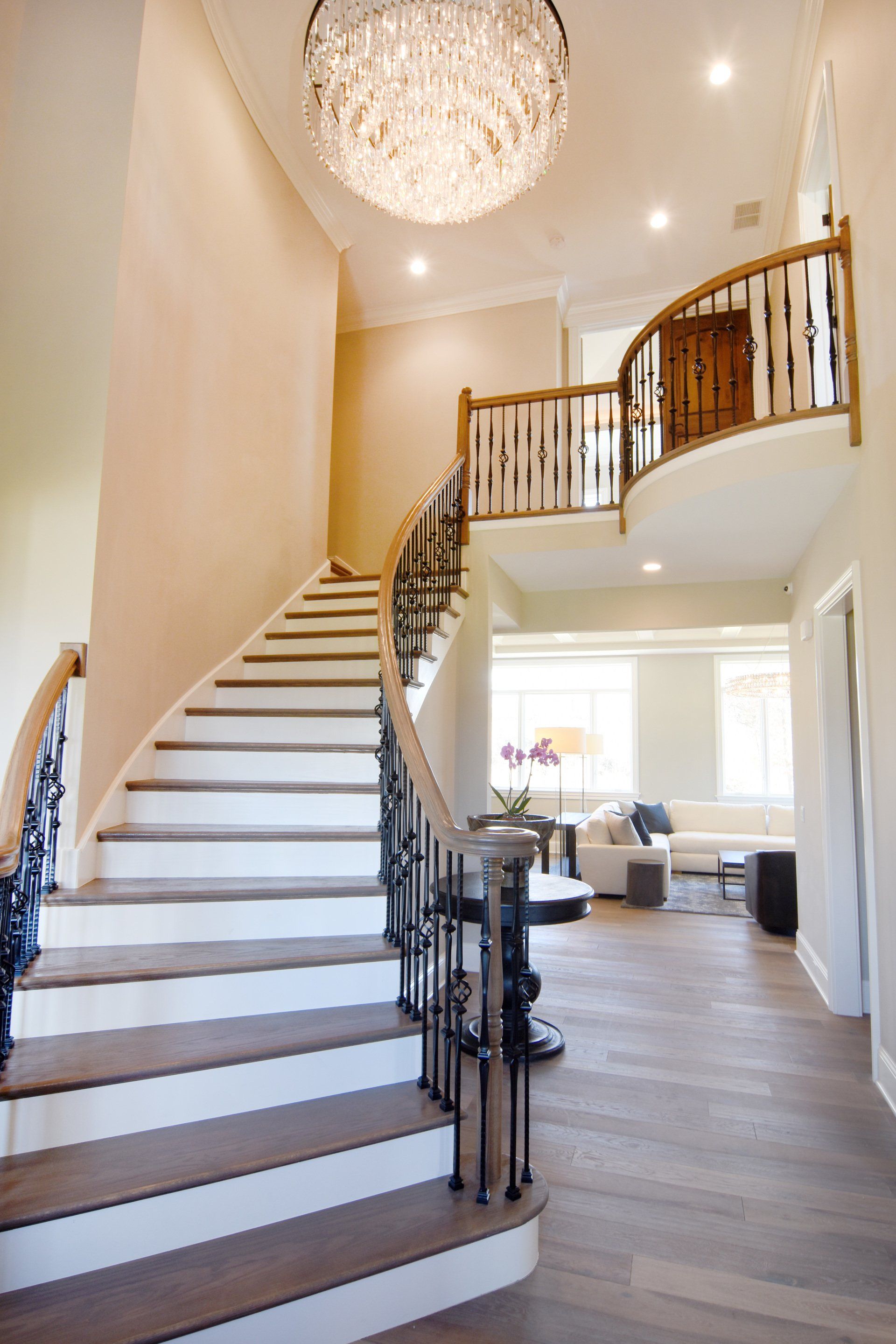 A curved staircase in a house with a chandelier hanging from the ceiling.